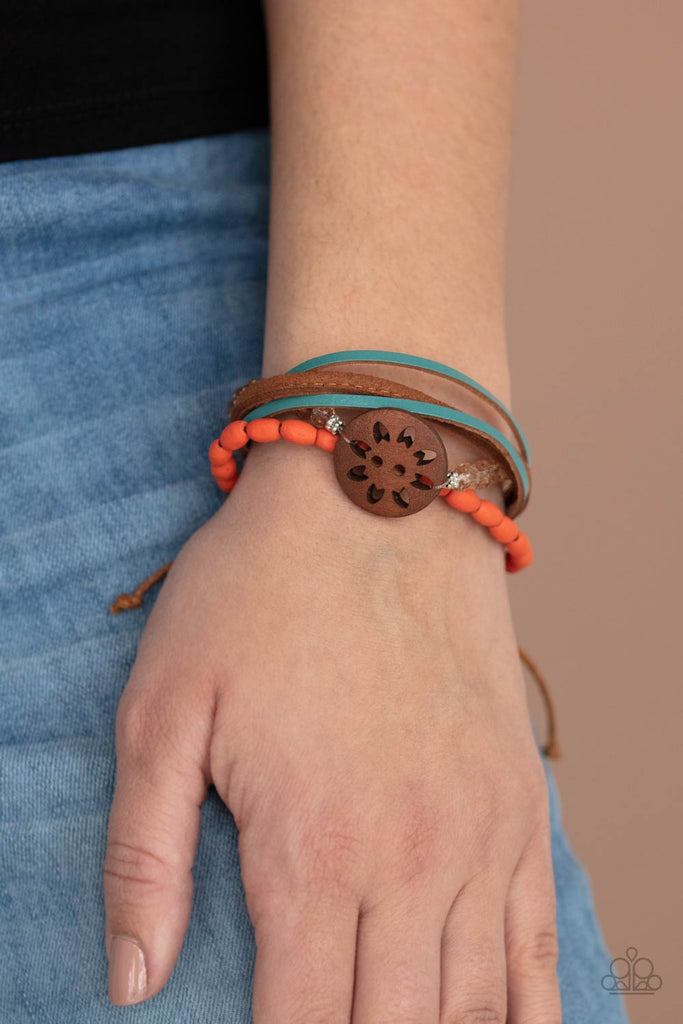 Featuring a wooden floral centerpiece, mismatched strands of orange wooden beads, blue leather, brown suede, and topaz crystal-like beads layer across the wrist for a seasonal flair. Features an adjustable sliding knot closure.  Sold as one individual bracelet.