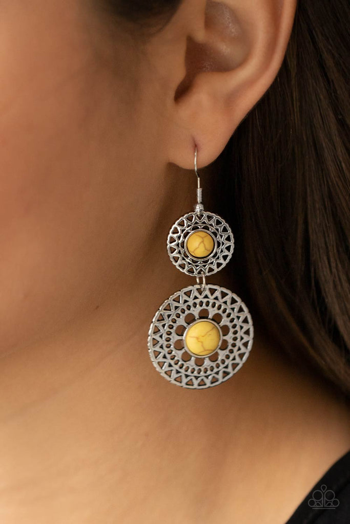 Stenciled in airy metallic sunburst patterns, a pair of silver mandala-like frames are dotted with sunny yellow stone centers as they link into a tribal inspired lure. Earring attaches to a standard fishhook fitting.  Sold as one pair of earrings.  