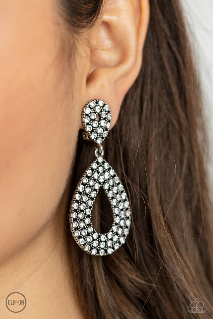 A white rhinestone encrusted silhouette teardrop attaches to the bottom of a dainty white rhinestone encrusted teardrop, creating a glamorous lure. Earring attaches to a standard clip-on fitting.  Sold as one pair of clip-on earrings.