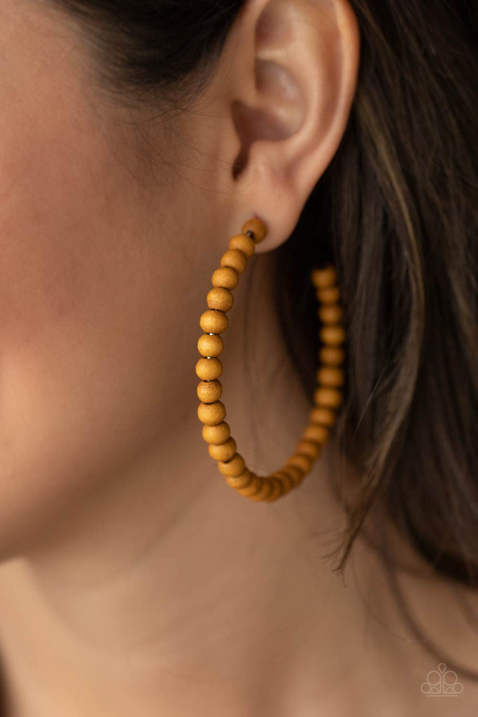 Brown wooden beads are threaded along a dainty wire, creating an earthy hoop. Earring attaches to a standard post fitting. Hoop measures approximately 2 1/2" in diameter.  Sold as one pair of hoop earrings.