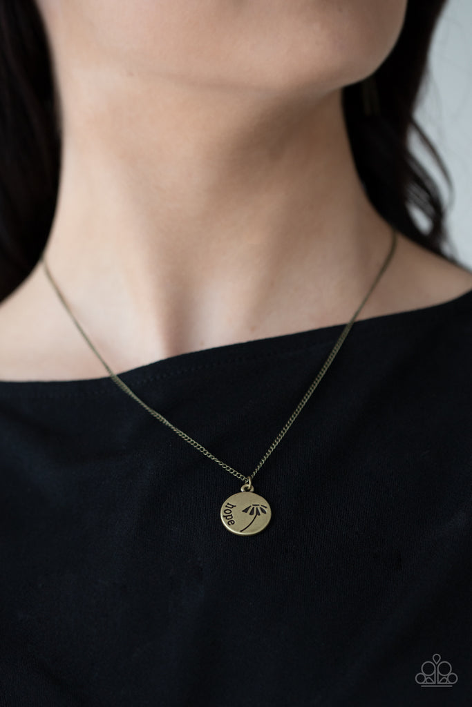 Stamped in a whimsical flower, a dainty brass disc is stamped in the word, "Hope," creating an inspirational pendant below the collar. Features an adjustable clasp closure.  Sold as one individual necklace. Includes one pair of matching earrings.