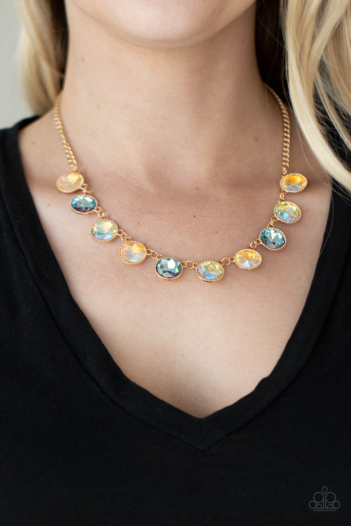 Featuring a UV iridescence, a sparkling display of peach, blue, and golden gems are encased into delicately textured gold frames as they link below the collar, creating a majestic statement piece. Features an adjustable clasp closure.  Sold as one individual necklace. Includes one pair of matching earrings.