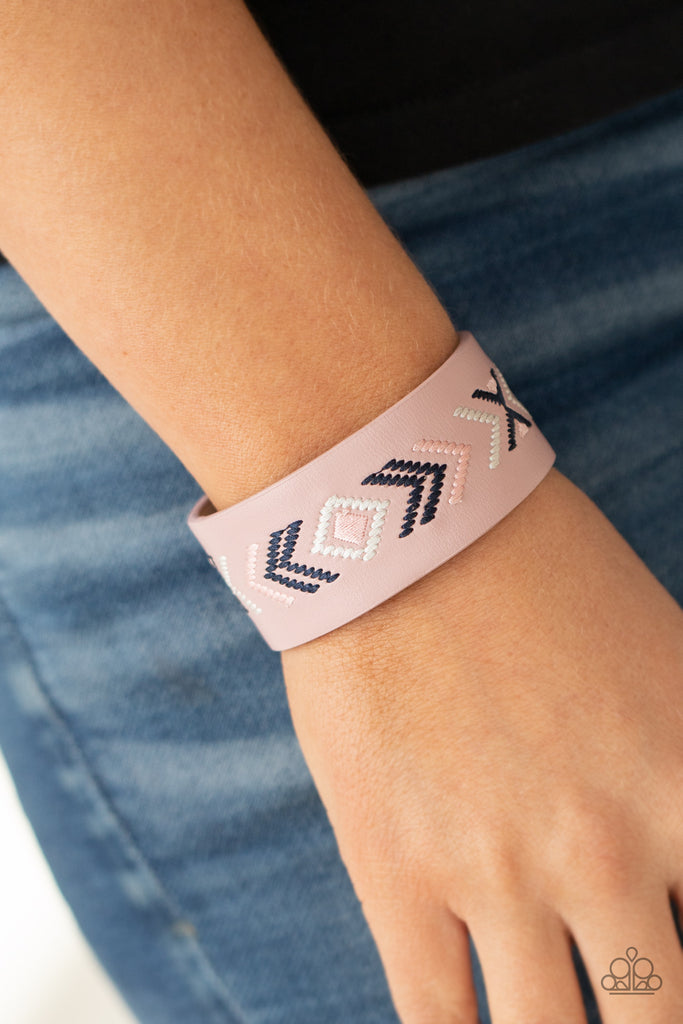 Pink, blue, and white thread is stitched across the front of a pink leather band, creating a colorful tribal inspired pattern. Features an adjustable snap closure.  Sold as one individual bracelet.  