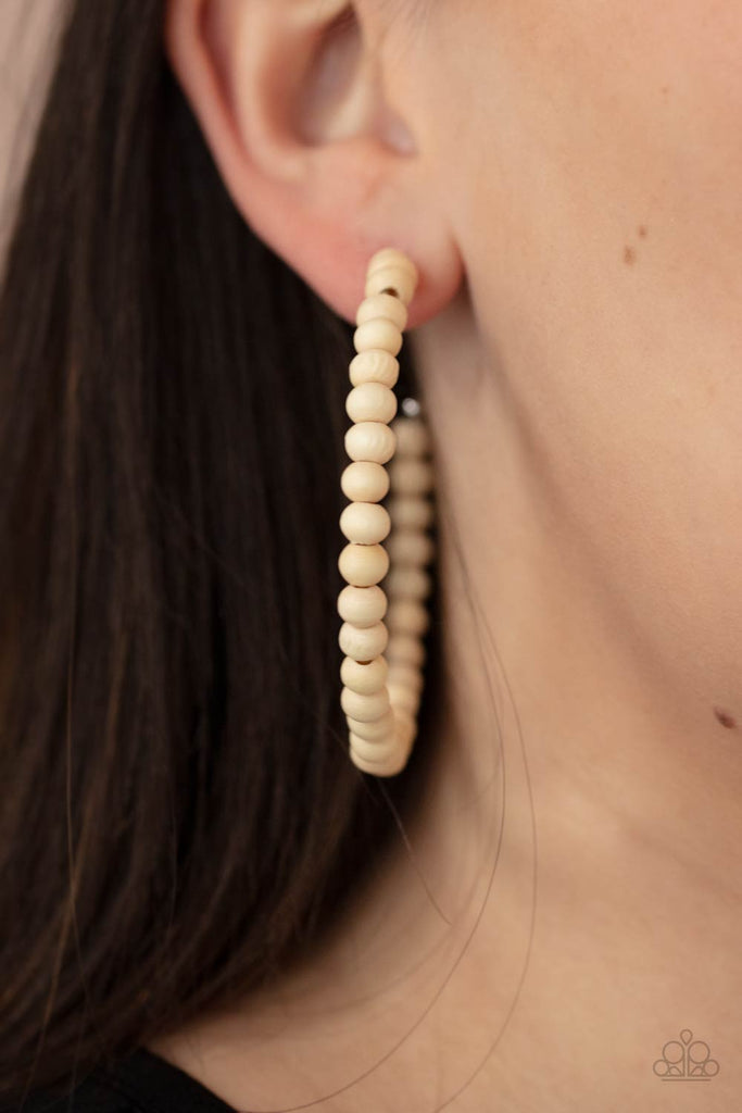 White wooden beads are threaded along a dainty wire, creating an earthy hoop. Earring attaches to a standard post fitting. Hoop measures approximately 2 1/2" in diameter.  Sold as one pair of hoop earrings.