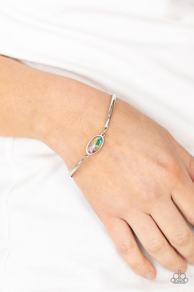 A collection of colorful wildflowers is encased in a glassy casing bordered in silver that attaches to two shiny silver bars around the wrist, creating a whimsically dainty centerpiece. Features an adjustable clasp closure.  Sold as one individual bracelet.