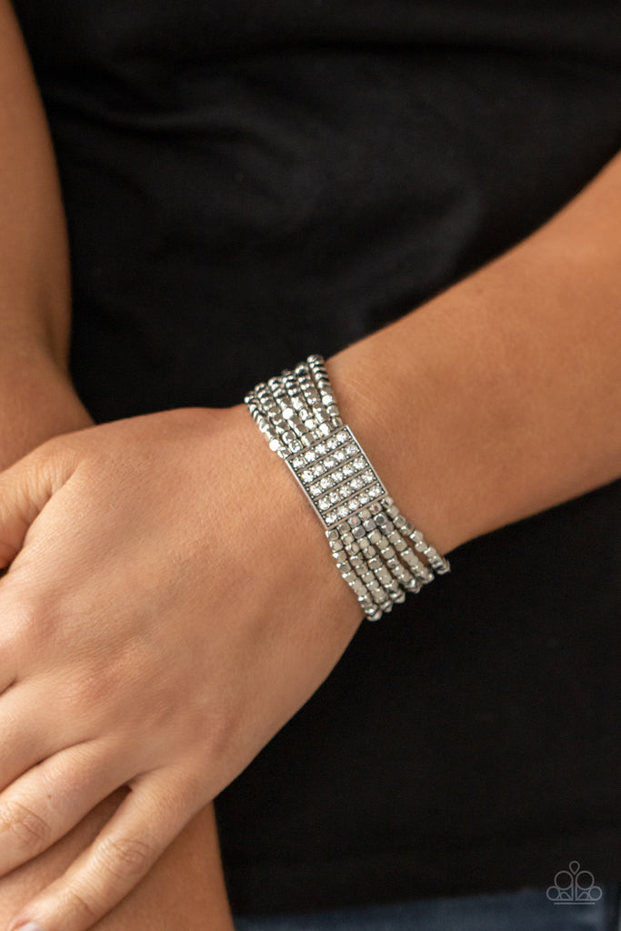 Held in place by a square centerpiece encrusted in row after row of dazzling rhinestones, a dainty collection of silver cube beads are threaded along stretchy bands around the wrist, creating shimmery layers.  Sold as one individual bracelet.