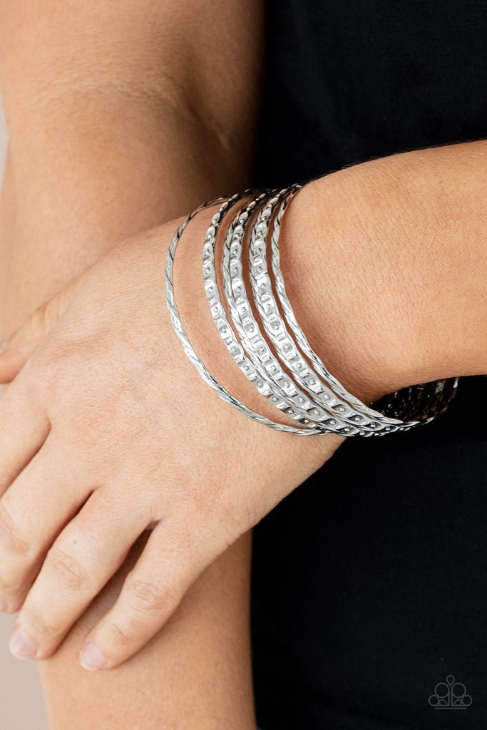 Embossed in slanted ribbons of textured and studded hammered patterns, trios of mismatched silver bangles stack across the wrist for an intense industrial vibe.  Sold as one set of six bracelets.