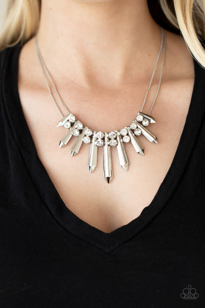 Pairs of glittery white rhinestones alternate between flared silver rods that are threaded along two rows of flat silver chains, creating a dangerous fringe below the collar. Features an adjustable clasp closure.  Sold as one individual necklace. Includes one pair of matching earrings.