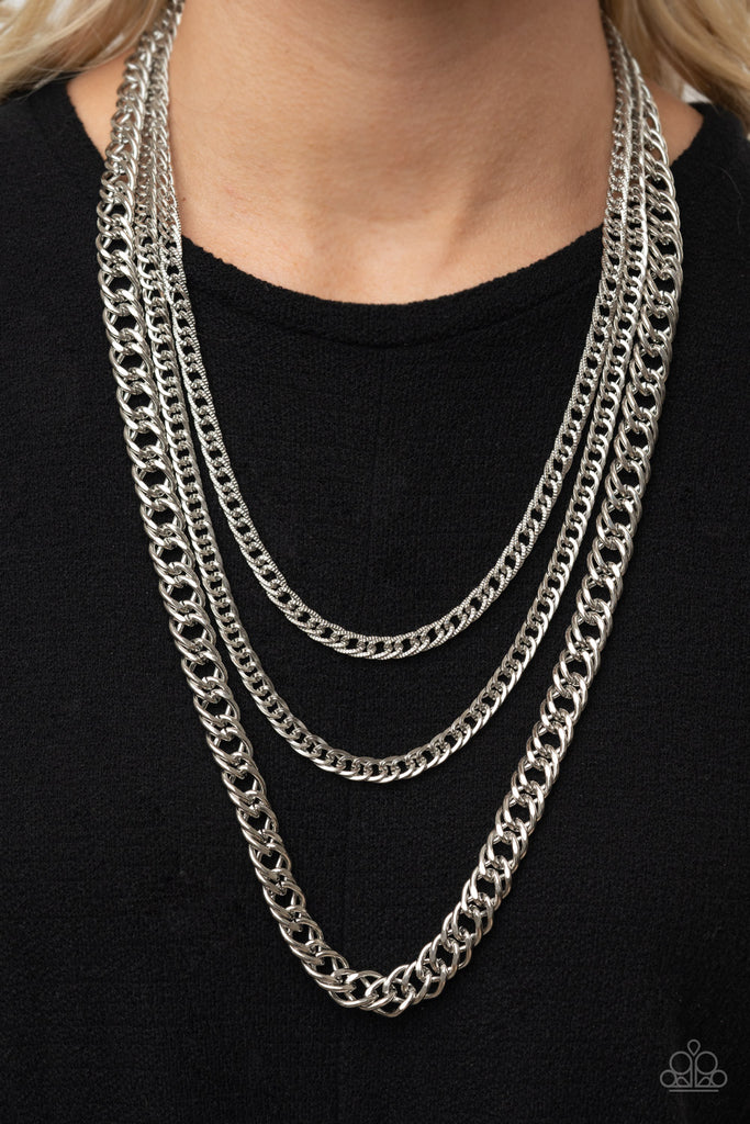 Bold layers of glistening silver chains of varying sizes and textures, fall like a weighty medal across the chest creating an edgy industrial effect. Features an adjustable clasp closure.  Sold as one individual necklace. Includes one pair of matching earrings.  