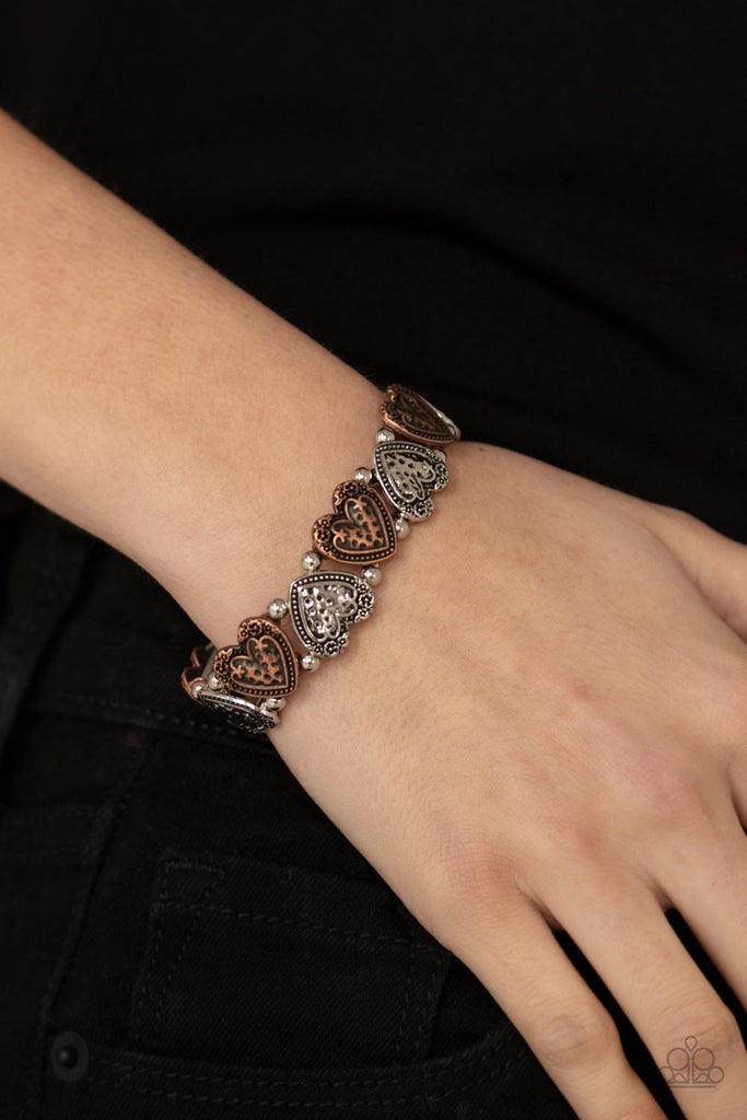 Adorned in dainty floral accents, hammered copper and silver heart frames and classic silver beads are threaded along stretchy bands around the wrist for a romantically rustic look.  Sold as one individual bracelet.