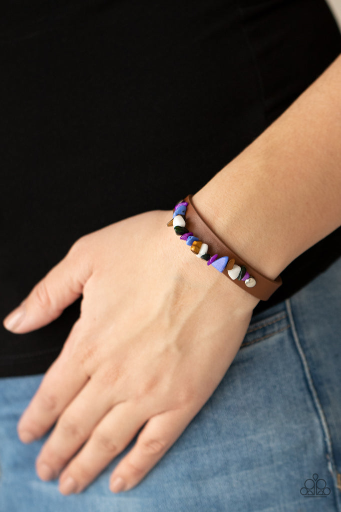 A strand of multicolored pebbles is studded in place across the front of a skinny brown leather band, creating a colorful earthy display around the wrist. Features an adjustable snap closure.  Sold as one individual bracelet.