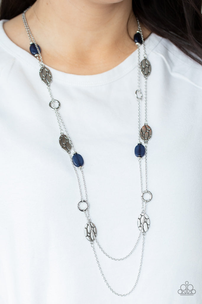 Textured silver links alternate between glassy blue accents and cobblestone patterned silver discs along two shimmery chains, creating whimsical layers across the chest. Features an adjustable clasp closure.  Sold as one individual necklace. Includes one pair of matching earrings.  