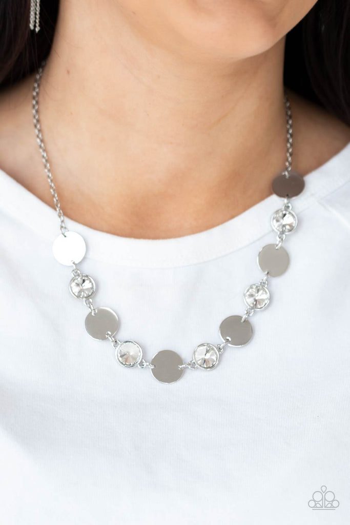 Shiny silver discs and oversized glassy white gems delicately link below the collar, creating a sparkly statement piece. Features an adjustable clasp closure.  Sold as one individual necklace. Includes one pair of matching earrings.  