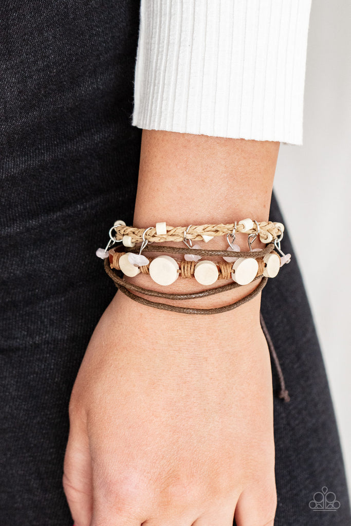 run-the-rapids-pink Assorted strands of cording and leather, featuring flat wooden beads and small pink polished stones dangling from silver fittings, layer across the wrist for an earthy handcrafted style. Features an adjustable sliding knot closure.  Sold as one individual bracelet.