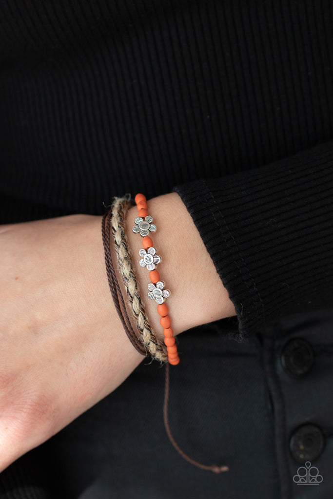 Three delightful etched silver flowers stand out on a strand of orange wooden beads. Paired with an assortment of braided twine and cording, the set wraps around the wrist for an earthy remix. Features an adjustable sliding knot closure.  Sold as one individual bracelet.