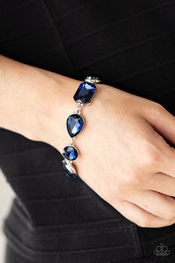 A collection of oversized round, teardrop, and emerald cut blue rhinestones delicately link around the wrist, creating a blinding statement piece. Features an adjustable clasp closure.  Sold as one individual bracelet.