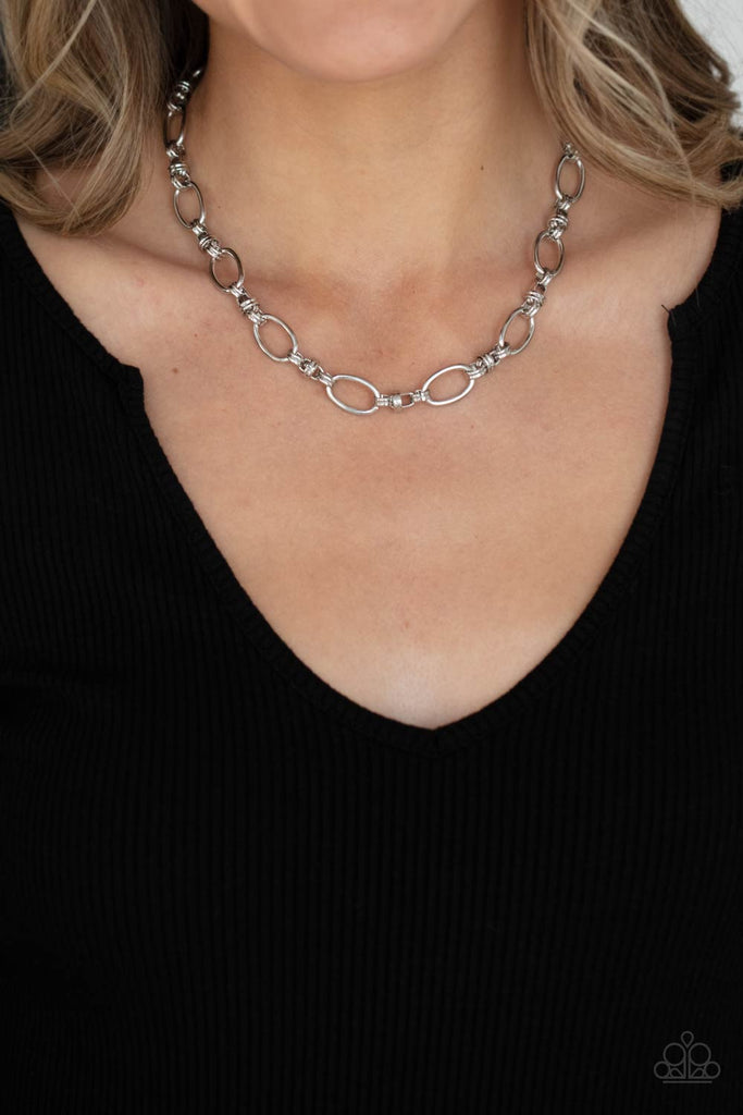 Pairs of joined silver links connect a collection of silver oval frames below the collar, creating an edgy chain. Features an adjustable clasp closure.  Sold as one individual necklace. Includes one pair of matching earrings.