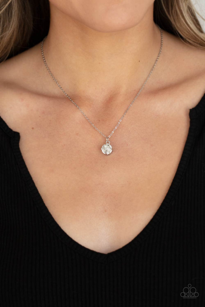 A glittery white rhinestone is fitted inside a pronged silver frame, creating a dramatically timeless pendant below the collar. Features an adjustable clasp closure.  Sold as one individual necklace. Includes one pair of matching earrings.