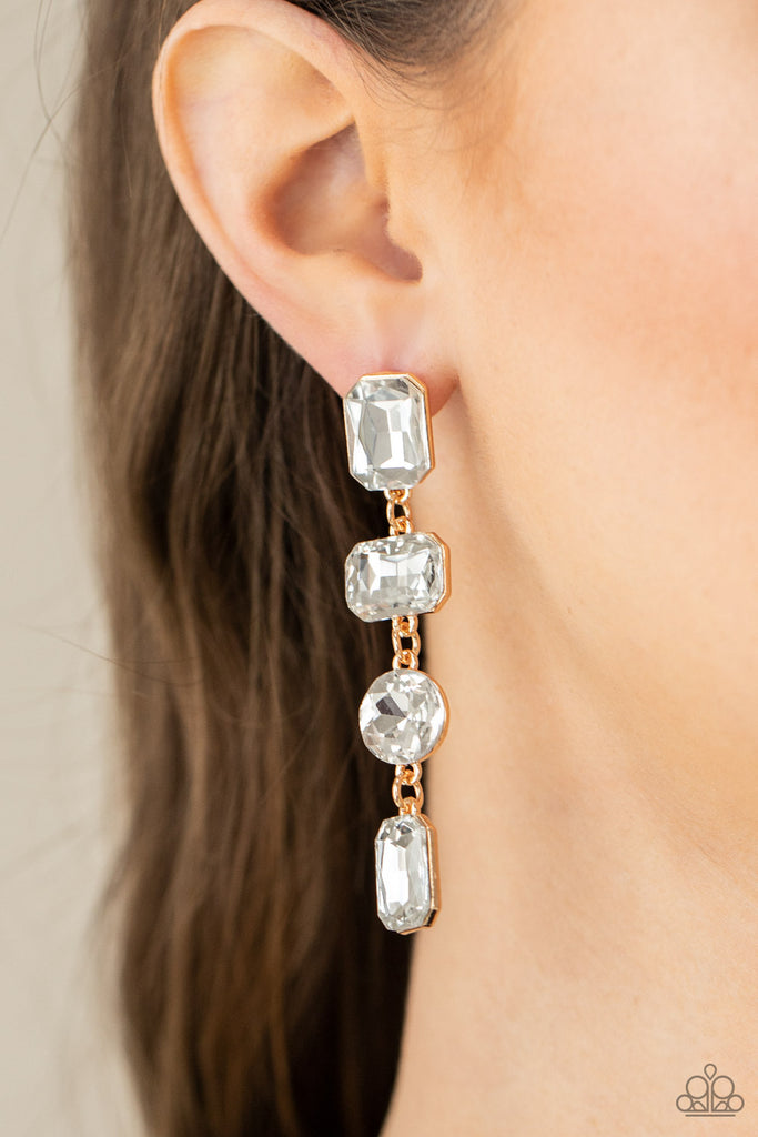 A strand of oversized round, teardrop, and emerald cut white rhinestones trickles from the ear, creating a jaw-dropping golden chandelier. Earring attaches to a standard post earring.  Sold as one pair of post earrings.