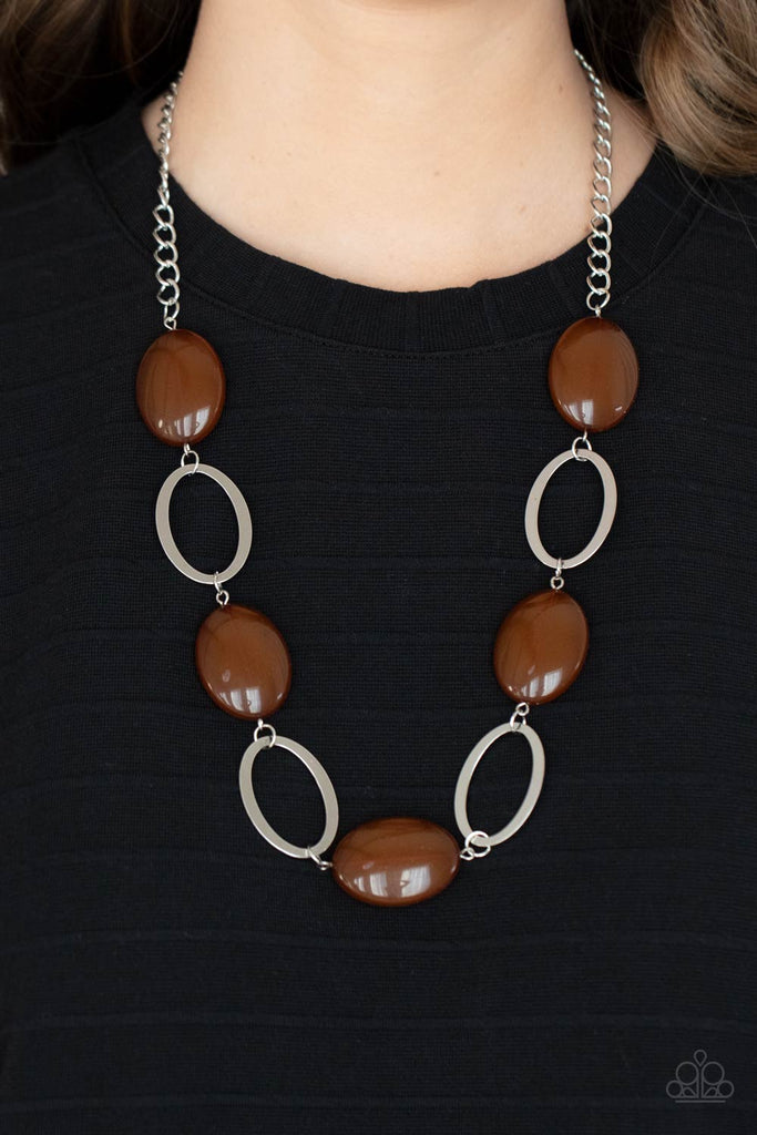 Shiny silver ovals and glassy brown oval beads delicately link across the chest, creating a whimsical pop of color. Features an adjustable clasp closure.  Sold as one individual necklace. Includes one pair of matching earrings.  