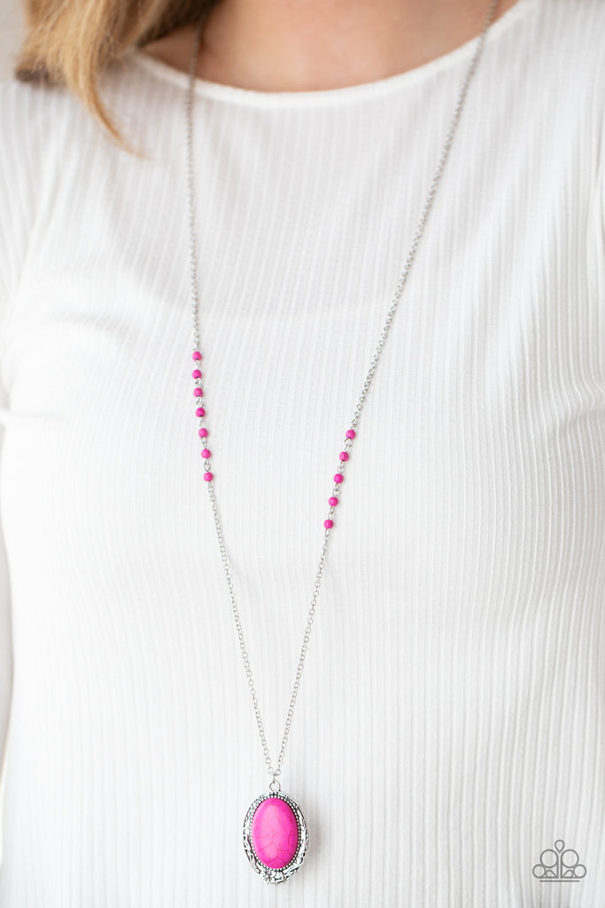 An oval pink stone bead pressed into an ornate silver frame embossed in floral vine-like patterns, creating a whimsical pendant at the bottom of a pink stone beaded chain. Features an adjustable clasp closure.  Sold as one individual necklace. Includes one pair of matching earrings.