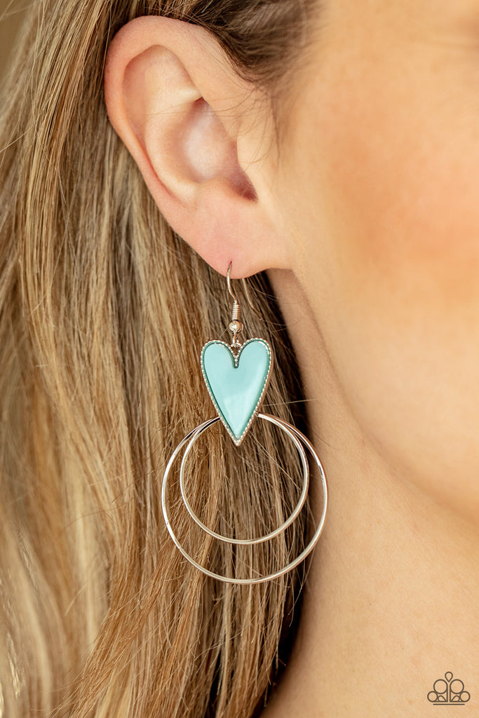 Dainty silver hoops attach to the bottom of a playful Cerulean heart frame, creating a flirtatious pop of color. Earring attaches to a standard fishhook fitting.  Sold as one pair of earrings.