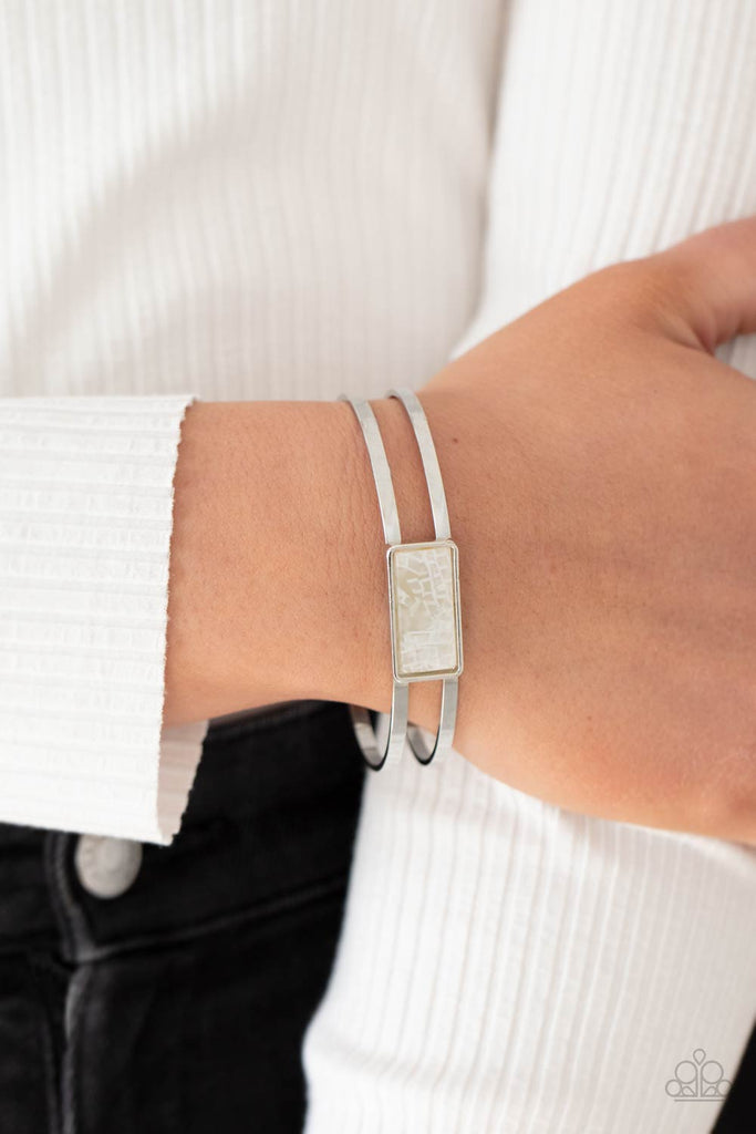 A bold shell-like acrylic accent is encased in a shiny silver rectangular frame that sits resolutely atop a double-bar silver cuff. Color and pattern may vary.  Sold as one individual bracelet.