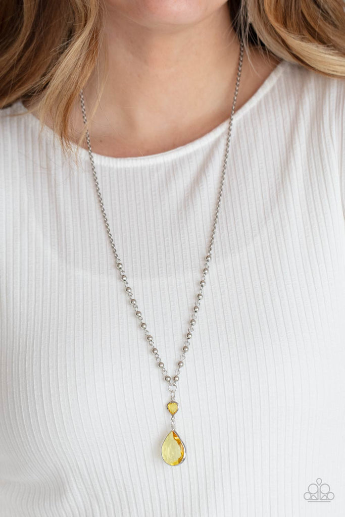 A magnificent Primrose teardrop gem steals the show as it dangles brilliantly from a lengthened silver chain. A small heart-shaped Primrose gem and shiny round beads accentuate the majestic look. Features an adjustable clasp closure.  Sold as one individual necklace. Includes one pair of matching earrings.