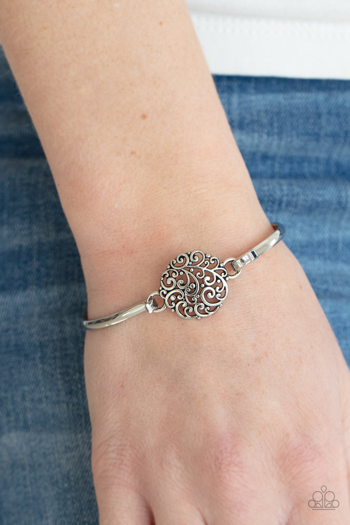 Shiny silver filigree swirls into a round frame that hooks to a dainty silver bangle-like cuff, creating a whimsical centerpiece. Features a hinge-like closure.  Sold as one individual bracelet.  