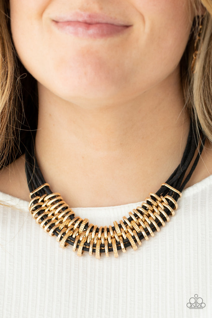 Bold and unapologetic, this hefty necklace gives off a hand-made feel with its multiple strands of black cording held together by industrial gold fittings that shift and slide. Features an adjustable clasp closure.  Sold as one individual necklace. Includes one pair of matching earrings.  