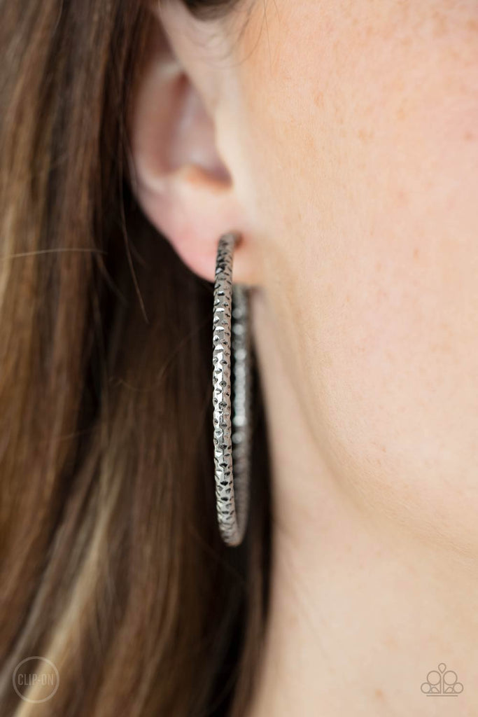 An oversized silver hoop featuring a porous-like texture sends off a subtle shimmer as it wraps around the ear. Earring attaches to a standard clip-on fitting. Hoop measures approximately 2" in diameter.  Sold as one pair of clip-on earrings.  