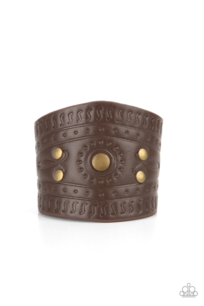 Dotted in rustic brass studs, a triangular piece of brown leather is stamped in indigenous inspired patterns for an urban flair. Features an adjustable snap closure.  Sold as one individual bracelet.