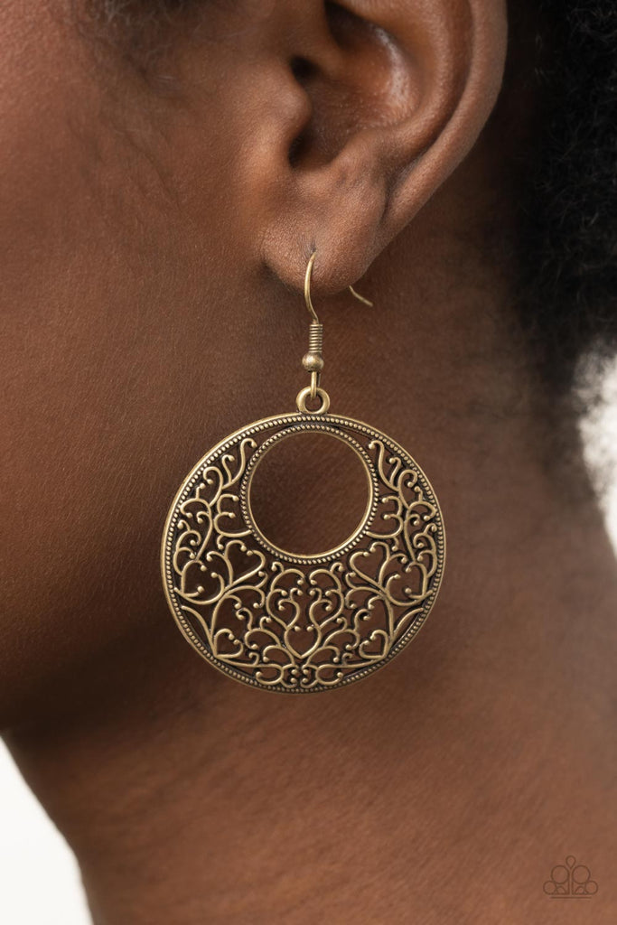 Brushed in an antiqued shimmer, vine-like brass filigree climbs the inside of a studded circular frame, creating a whimsical centerpiece. Earring attaches to a standard fishhook fitting.  Sold as one pair of earrings.