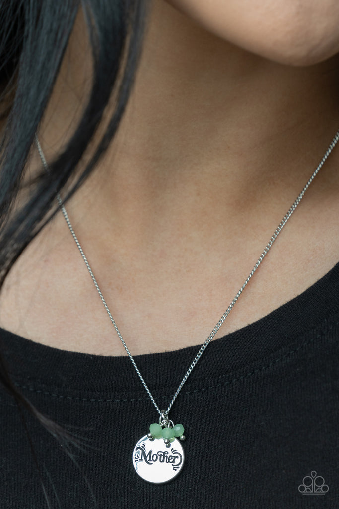 A dainty cluster of opaque Green Ash beads delicately joins a shiny silver disc stamped in the word, "Mother," along a classic silver chain, creating a whimsical pendant below the collar. Features an adjustable clasp closure.  Sold as one individual necklace. Includes one pair of matching earrings.