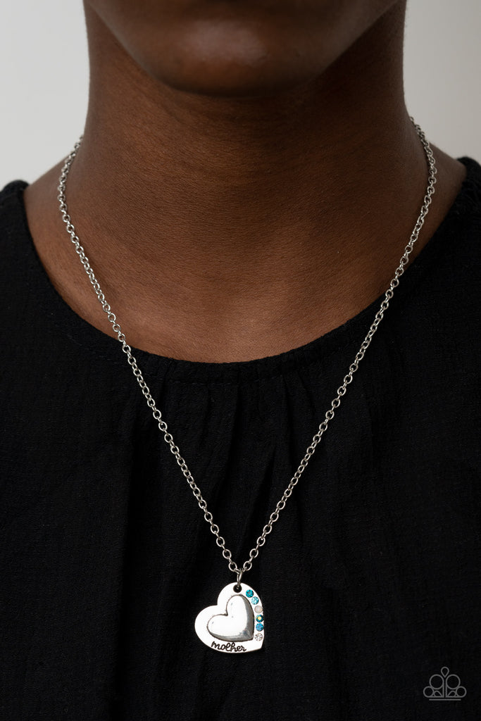 Stamped in the word, "Mother," an embossed heart pendant is encrusted in a row of blue, white, and iridescent rhinestones, creating a sparkly sentimental centerpiece below the collar. Features an adjustable clasp closure.  Sold as one individual necklace. Includes one pair of matching earrings.  