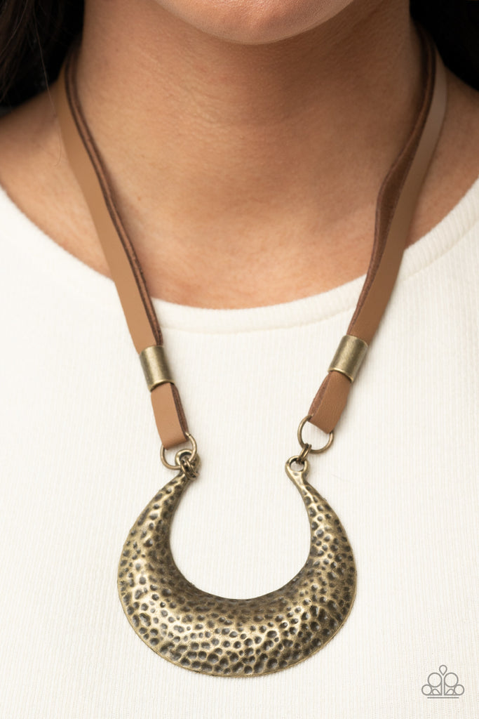 Infused with antiqued brass beads, strips of brown leather link to an oversized half moon pendant that is hammered in a bold brass finish, creating a rustic statement piece below the collar. Features an adjustable clasp closure.  Sold as one individual necklace. Includes one pair of matching earrings.  
