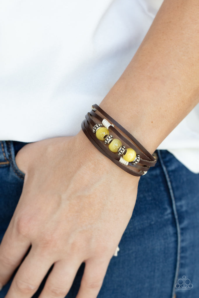 Infused with studded silver accents, a row of Illuminating cat's eye stone beads adorn the centermost strand of layered leather bands around the wrist for a colorful seasonal look. Features an adjustable sliding knot closure.  Sold as one individual bracelet.
