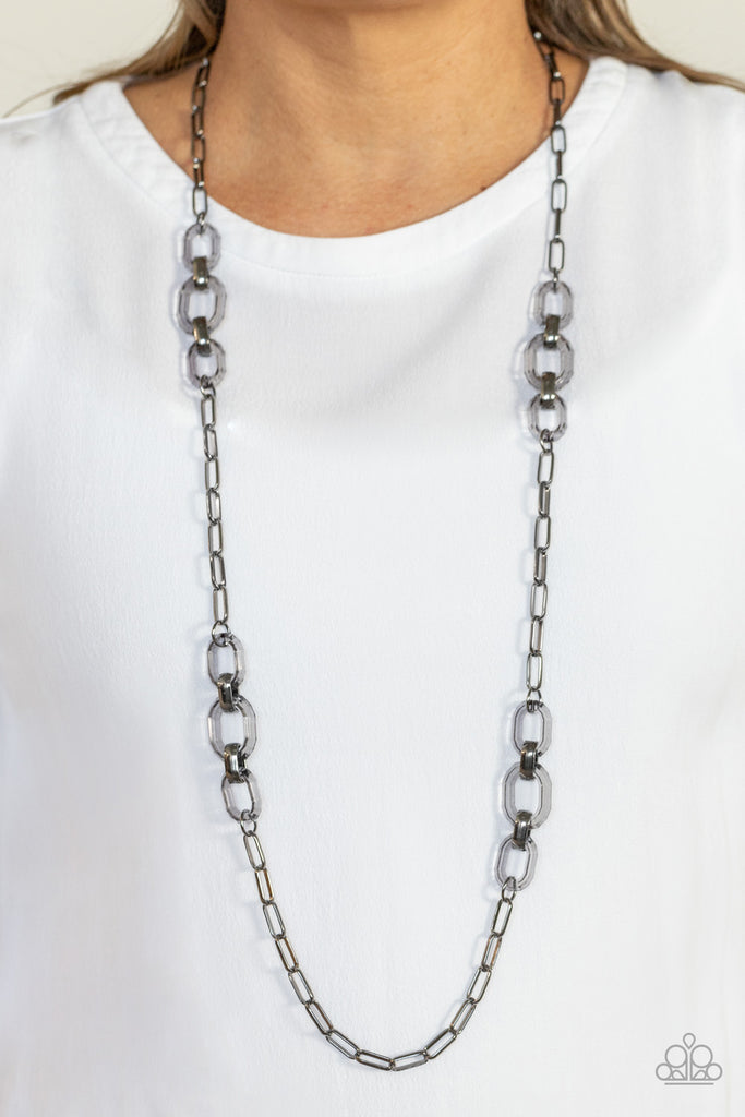 Sections of oversized clear acrylic and bold gunmetal links connect with an exaggerated gunmetal chain across the chest, creating an intense industrial display. Features an adjustable clasp closure.  Sold as one individual necklace. Includes one pair of matching earrings.