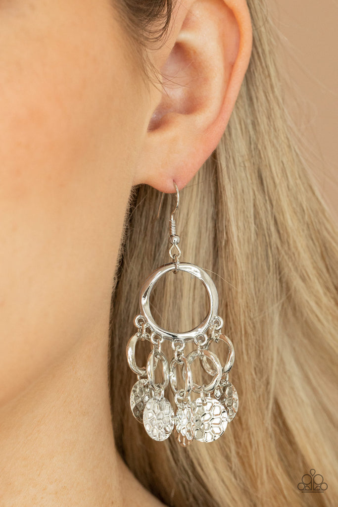 Embossed in tactile geometric patterns, shiny silver discs swing from the bottom of dainty silver rings at the bottom of an asymmetrical silver ring for a noise-making fashion. Earring attaches to a standard fishhook fitting.  Sold as one pair of earrings.