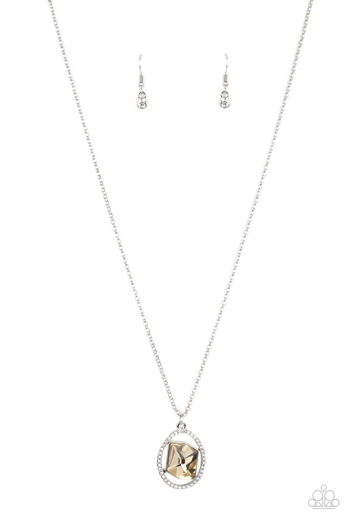 A raw cut topaz gem asymmetrically adorns the center of a warped white rhinestone oval frame, creating an extra sparkly pendant at the bottom of a classic silver frame. Features an adjustable clasp closure.  Sold as one individual necklace. Includes one pair of matching earrings.