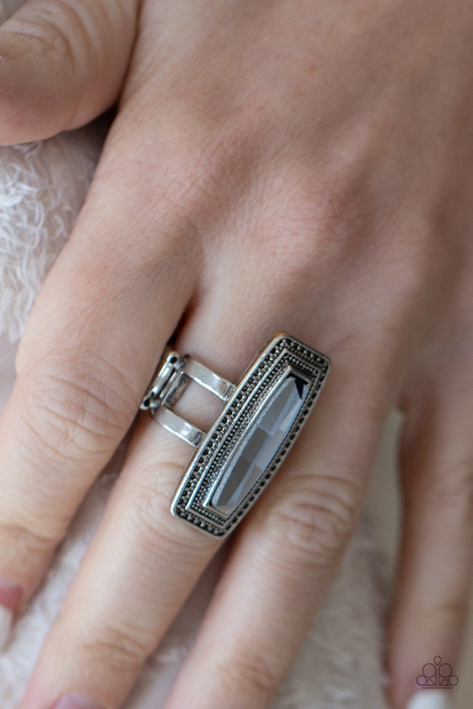 An elongated smoky gem is pressed into the center of a studded silver frame atop layered silver bands, creating a stellar centerpiece atop the finger. Features a stretchy band for a flexible fit.  Sold as one individual ring.  