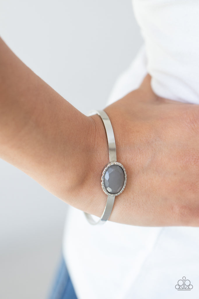 A misty gray gem is pressed into the center of a hammered silver fitting atop a thick silver bangle, creating an ethereal centerpiece.  Sold as one individual bracelet.