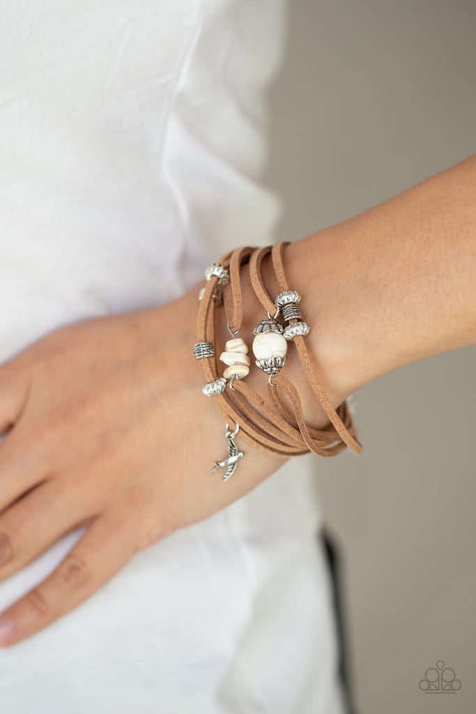 Infused with a dainty silver bird charm, dainty strands of brown suede are adorned in mismatched silver accents and white stones for an earthy layered look. Features an adjustable clasp closure.  Sold as one individual bracelet.