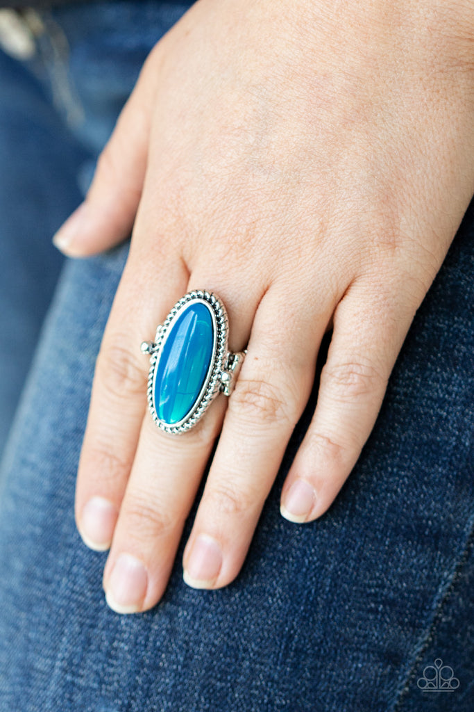 Featuring a glassy iridescence, an oval Blue Tint acrylic bead is pressed into the center of textured silver fittings, creating a mystical centerpiece atop the finger. Features a dainty stretchy band for a flexible fit.  Sold as one individual ring.