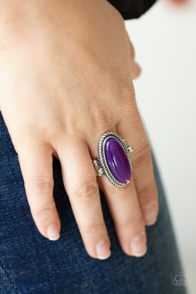Featuring a glassy iridescence, an oval purple acrylic bead is pressed into the center of textured silver fittings, creating a mystical centerpiece atop the finger. Features a dainty stretchy band for a flexible fit.  Sold as one individual ring.  