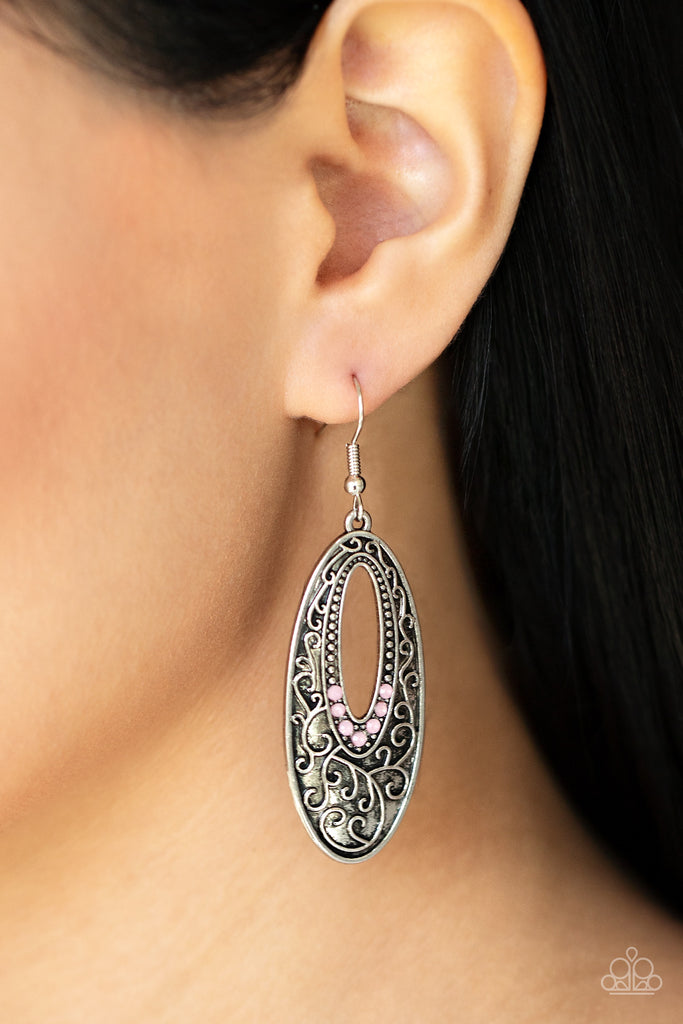 Dainty silver studs fade into dewy pink rhinestones around the airy center of an oval silver frame that is embossed in a vine-like scroll, creating an ethereally whimsical frame. Earring attaches to a standard fishhook fitting.  Sold as one pair of earrings.