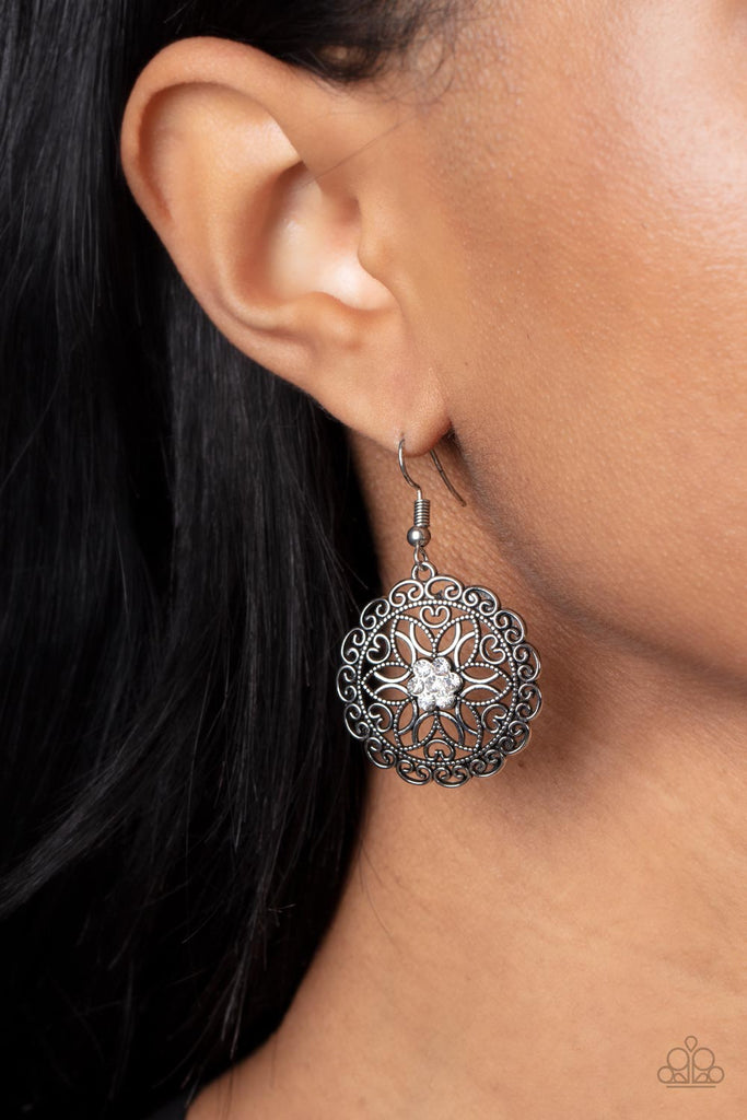  Overlapping silver petals fan out from a sparkly white rhinestone center inside a frilly ring of silver filigree, resulting in a whimsical floral frame. Earring attaches to a standard fishhook fitting.  Sold as one pair of earrings.
