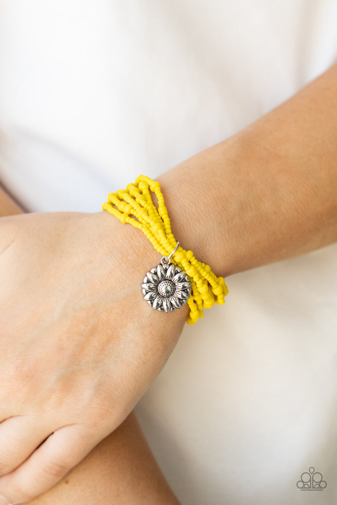 A shiny silver floral charm glides along stretchy strands of mismatched yellow seed beads, creating vibrant layers around the wrist.  Sold as one individual bracelet.