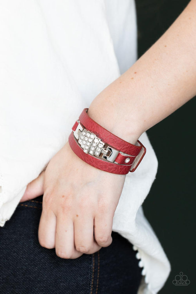 A white rhinestone silver centerpiece is studded in place by white rhinestone encrusted silver studs across the spliced center of a red leather band, creating a glittery urban look around the wrist. Features an adjustable snap closure.  Sold as one individual bracelet.