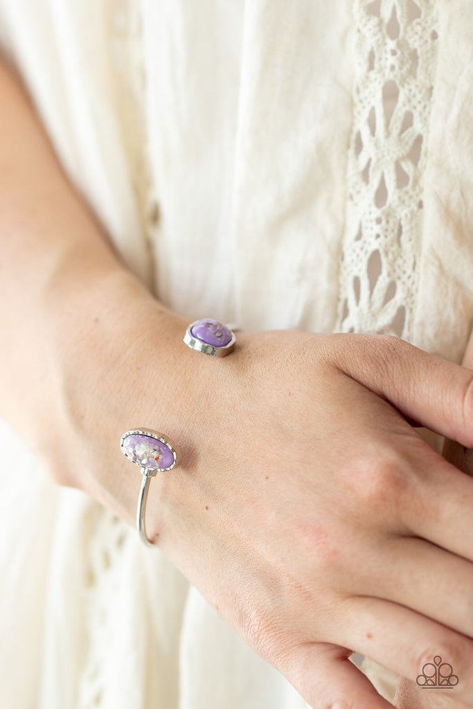 Flecks of iridescent shell-like pieces are encased inside two mismatched glassy purple beads at both ends of a dainty silver open-faced cuff. The shimmery beads are encased in imperfectly hammered silver frames, adding a whimsy finish to the bubbly display.  Sold as one individual bracelet.